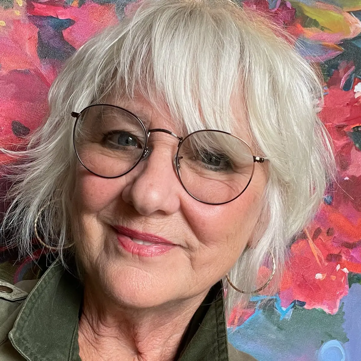 Sandra Gittleman, Fine Art Painter, smiling in front of her colorful abstract painting